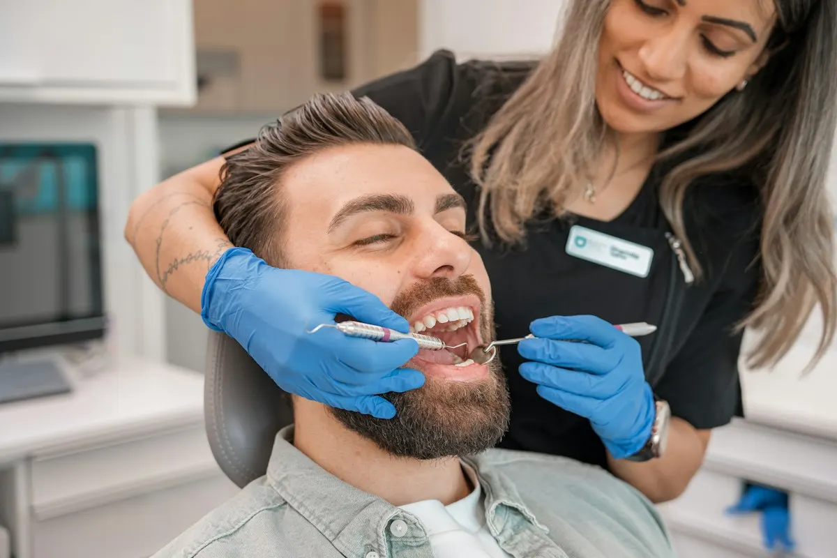 Hygienist cleaning a smiling patient’s teeth