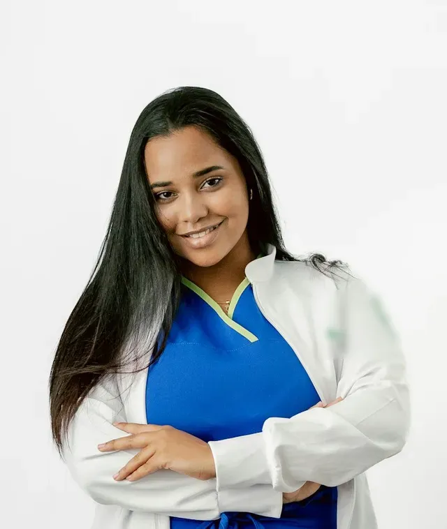 Marisol Vega, dental hygienist, in blue scrubs and a white coat