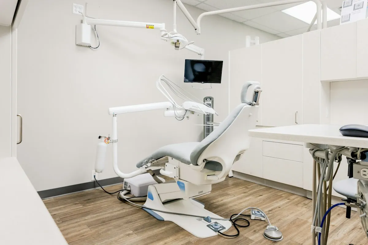 Bright treatment room with a dental chair and wood floor