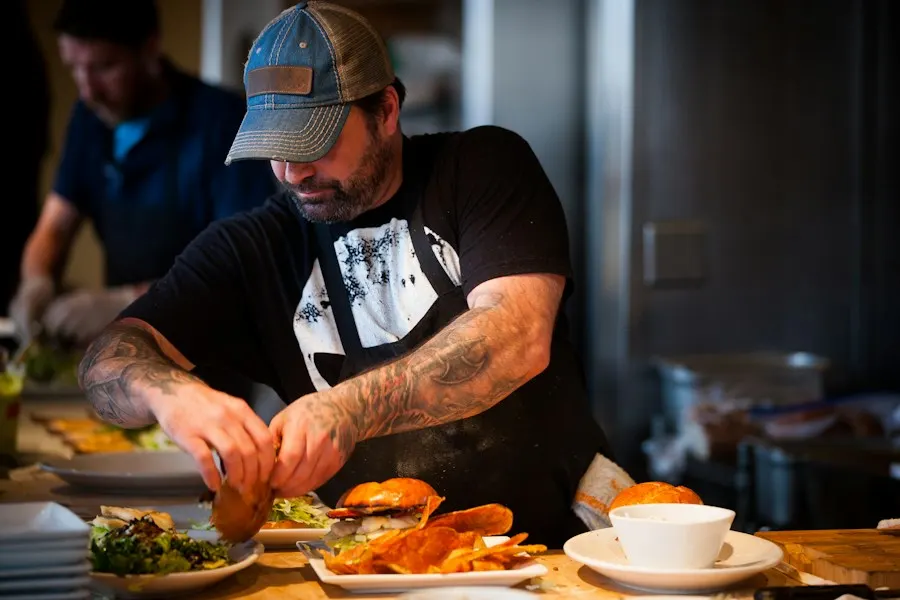 A cook in a cap finishing plates on the line
