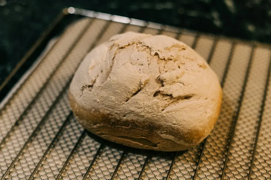 A round loaf of sourdough cooling on a wire rack