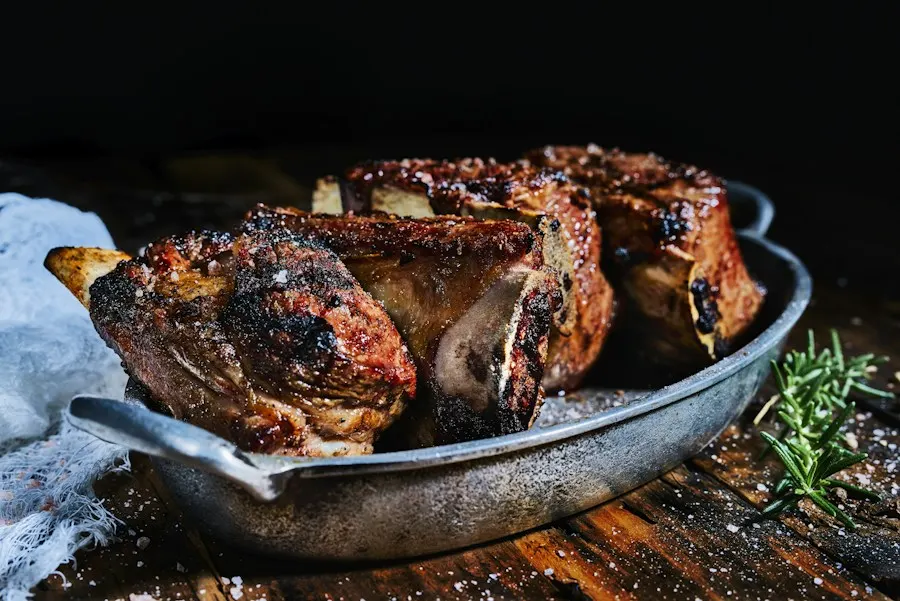 Slow-roasted lamb shoulder in a steel pan with rosemary