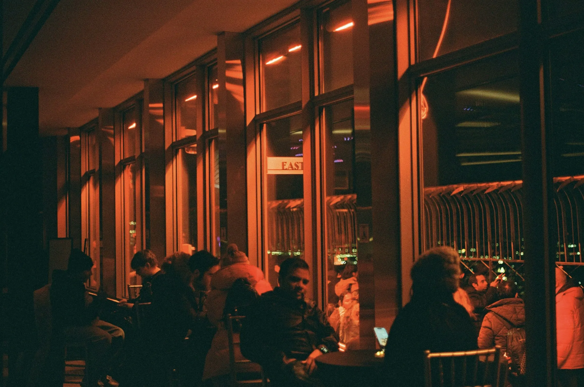 The Ember & Oak dining room on a busy evening, lit warm orange against tall windows