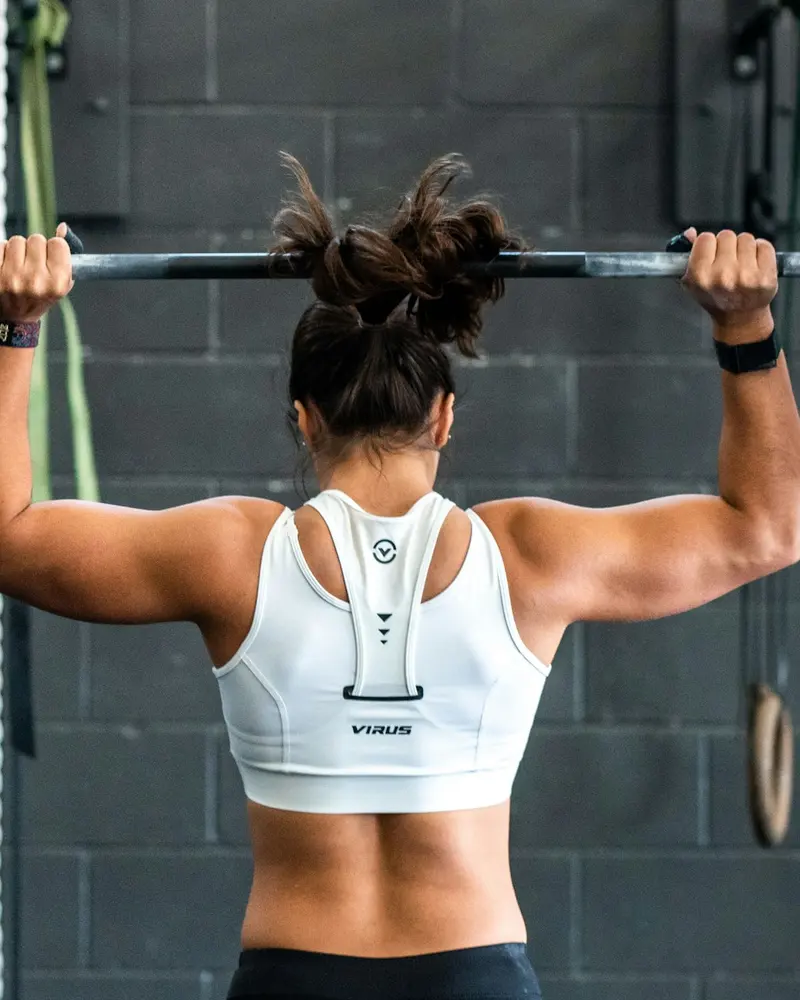 Member pressing a barbell overhead in a squat rack