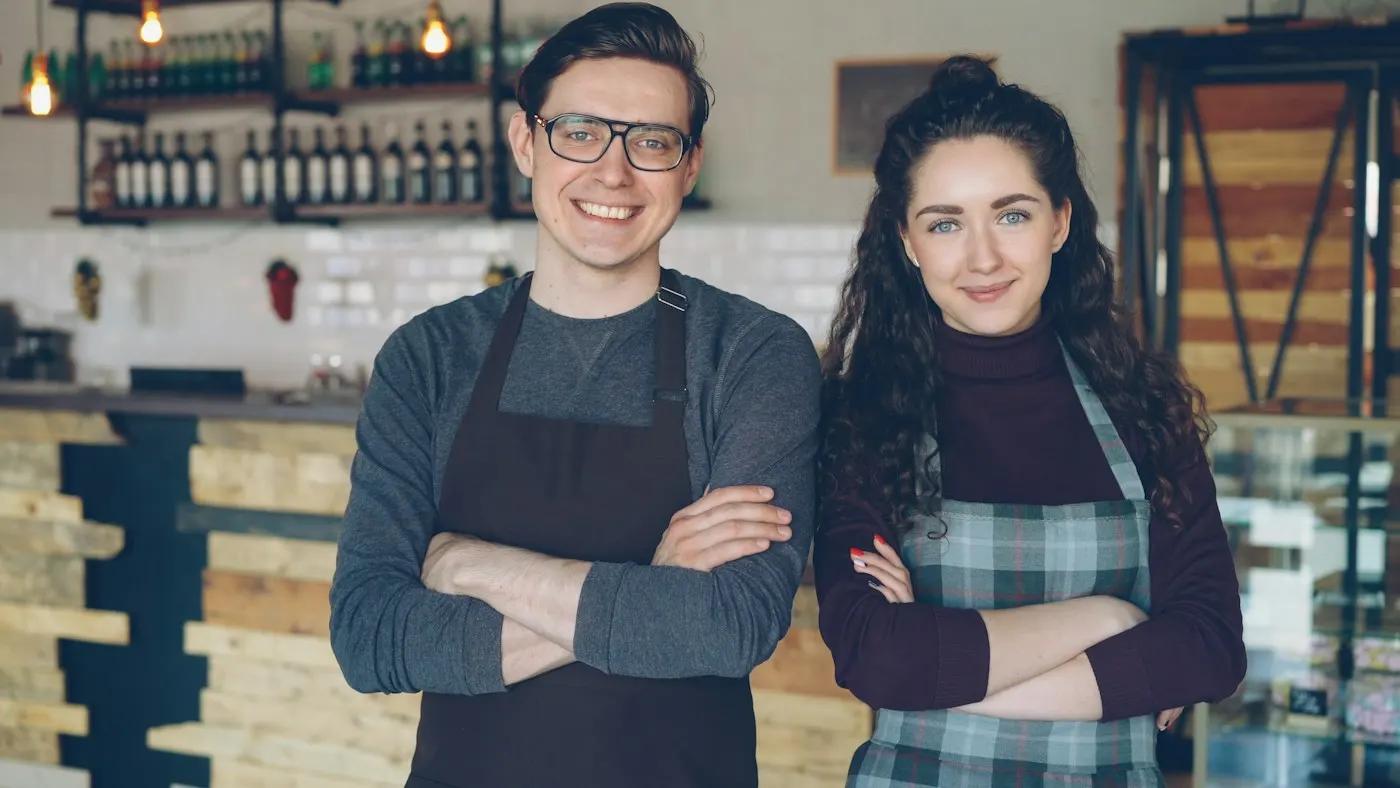 Nora and Ben, the founders, standing behind the café counter in aprons