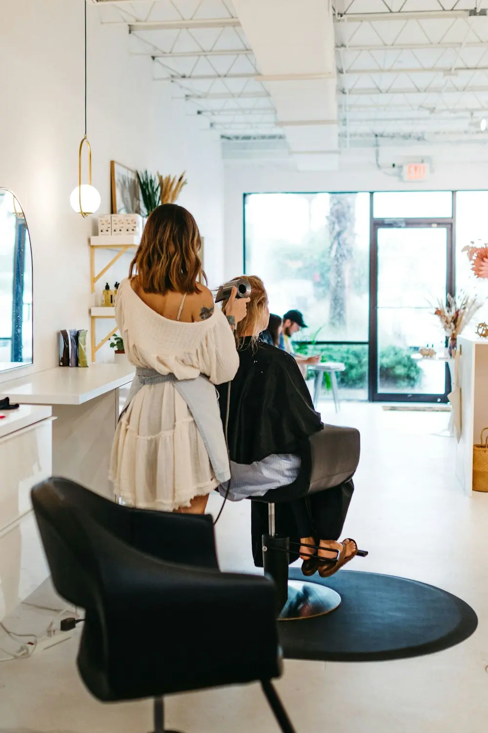 Claire working on a client’s colour at the front of the bright, plant-filled salon