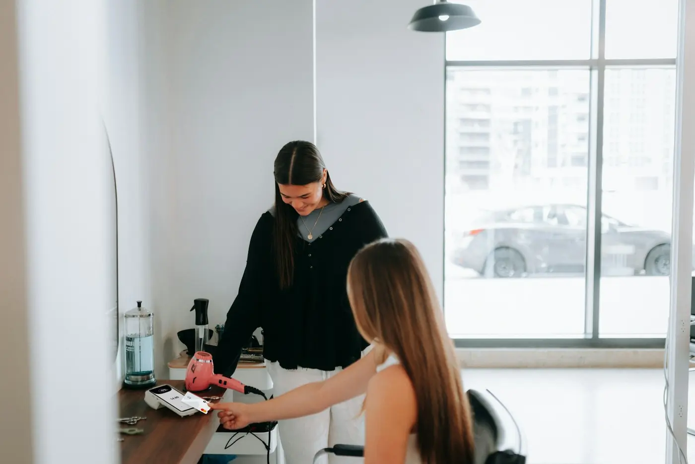 Stylist talking with a client before her appointment by a large window