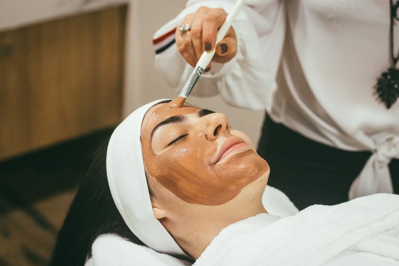 Client relaxing during a facial with a mask being applied
