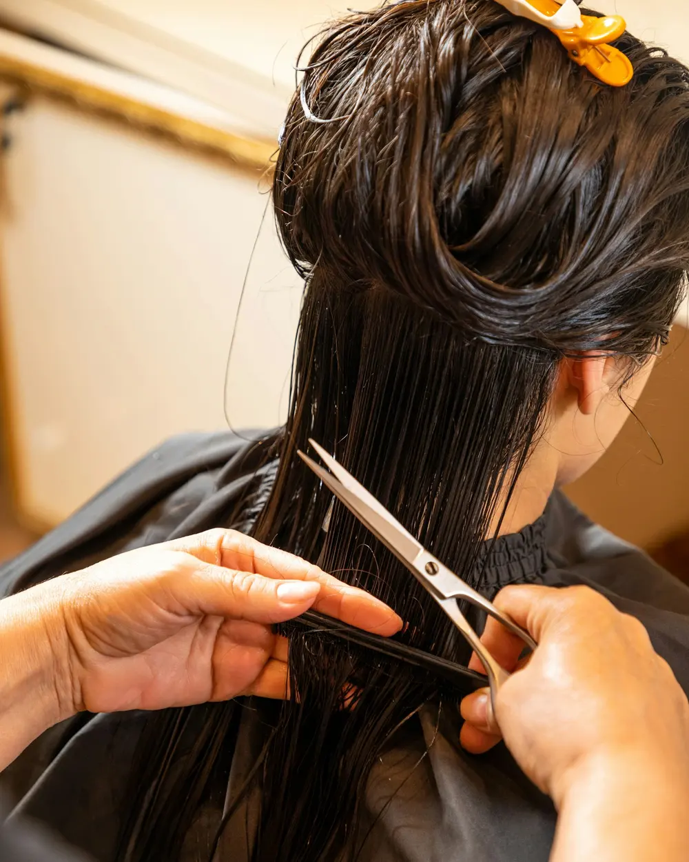 Stylist cutting a client’s dark hair with scissors