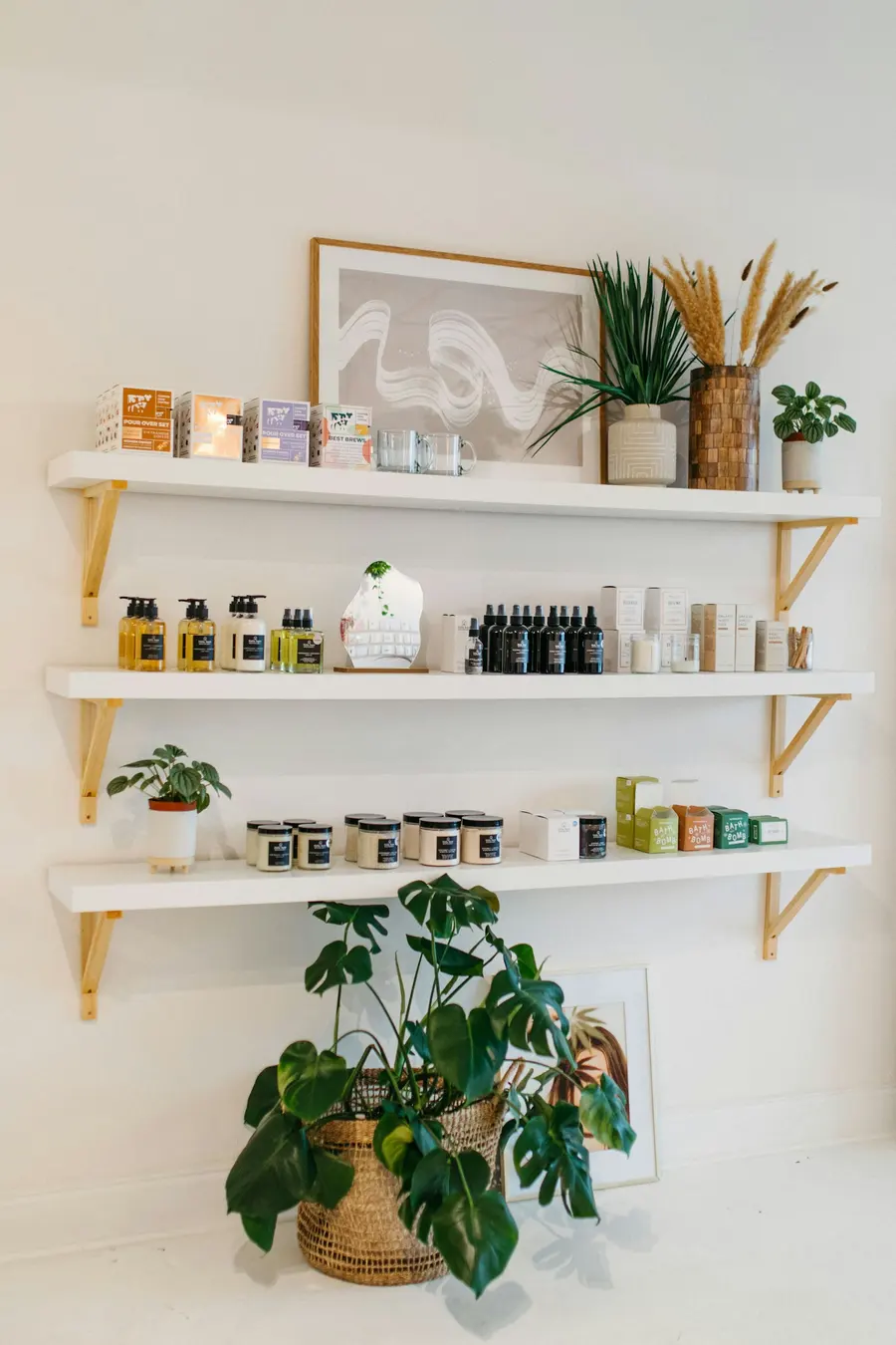 Wall shelves holding hair and skin products next to houseplants
