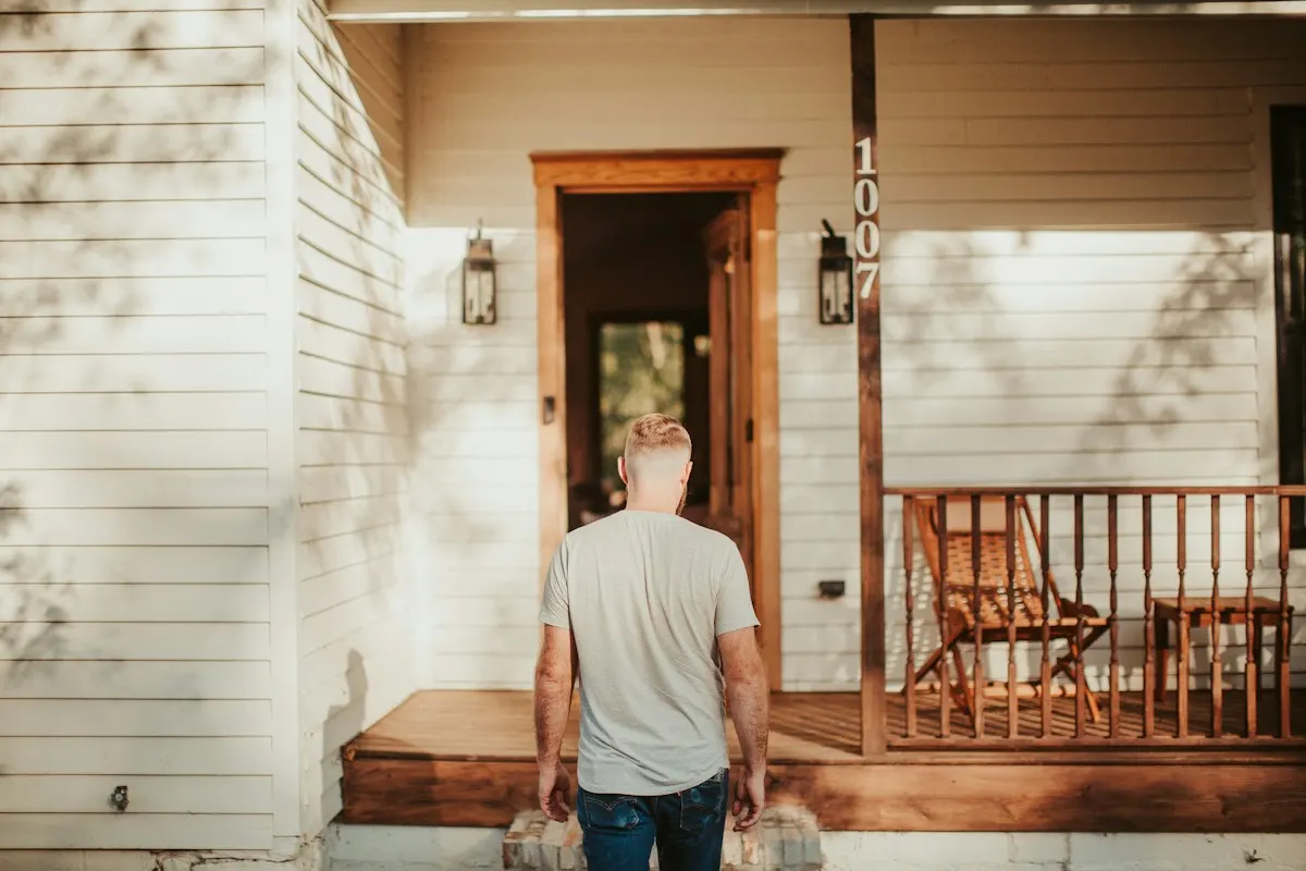 An estimator arriving at the front porch of a white clapboard house