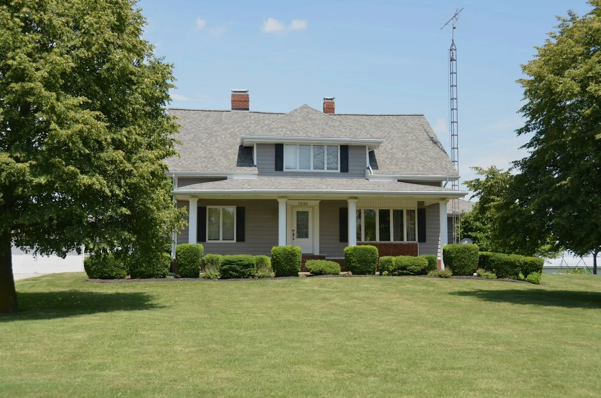 Grey farmhouse with a wide front porch and a new shingle roof