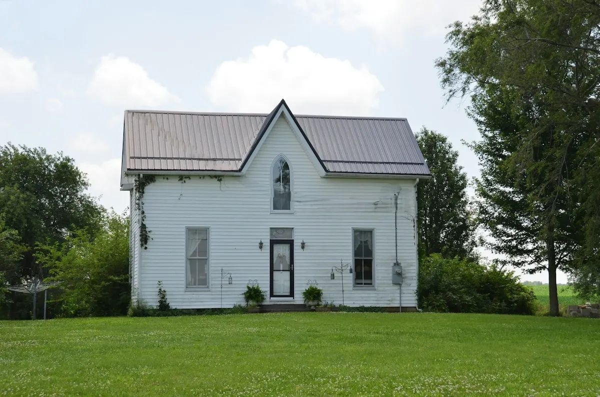 White Gothic Revival farmhouse with a new standing-seam metal roof