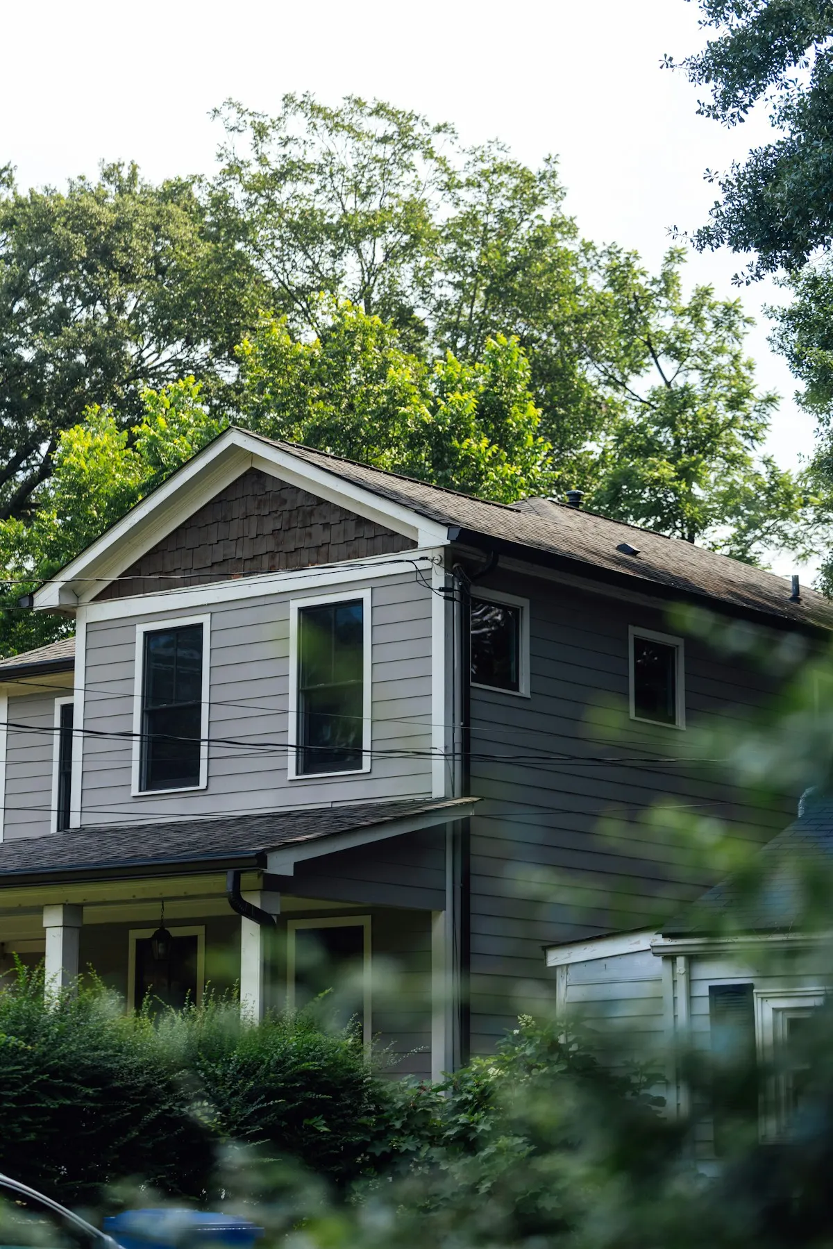 Grey two-story home among trees after a storm repair