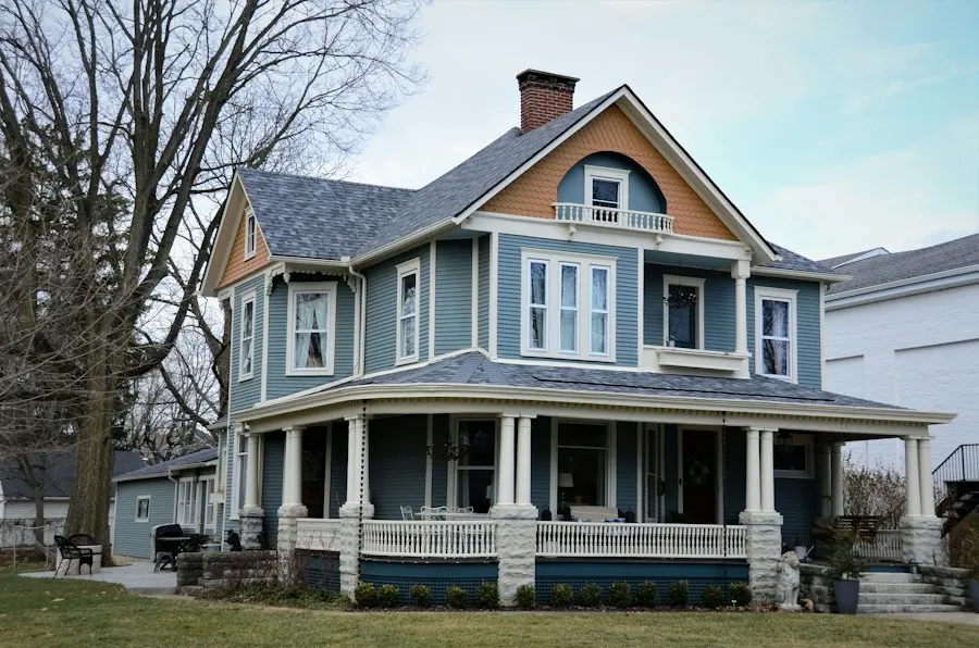 A blue Victorian house with new seamless gutters along the porch roof
